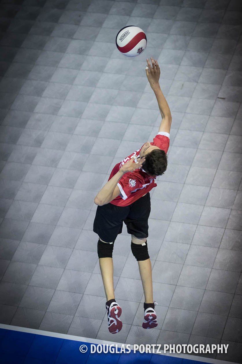 Volleyboll player serves ball overhead